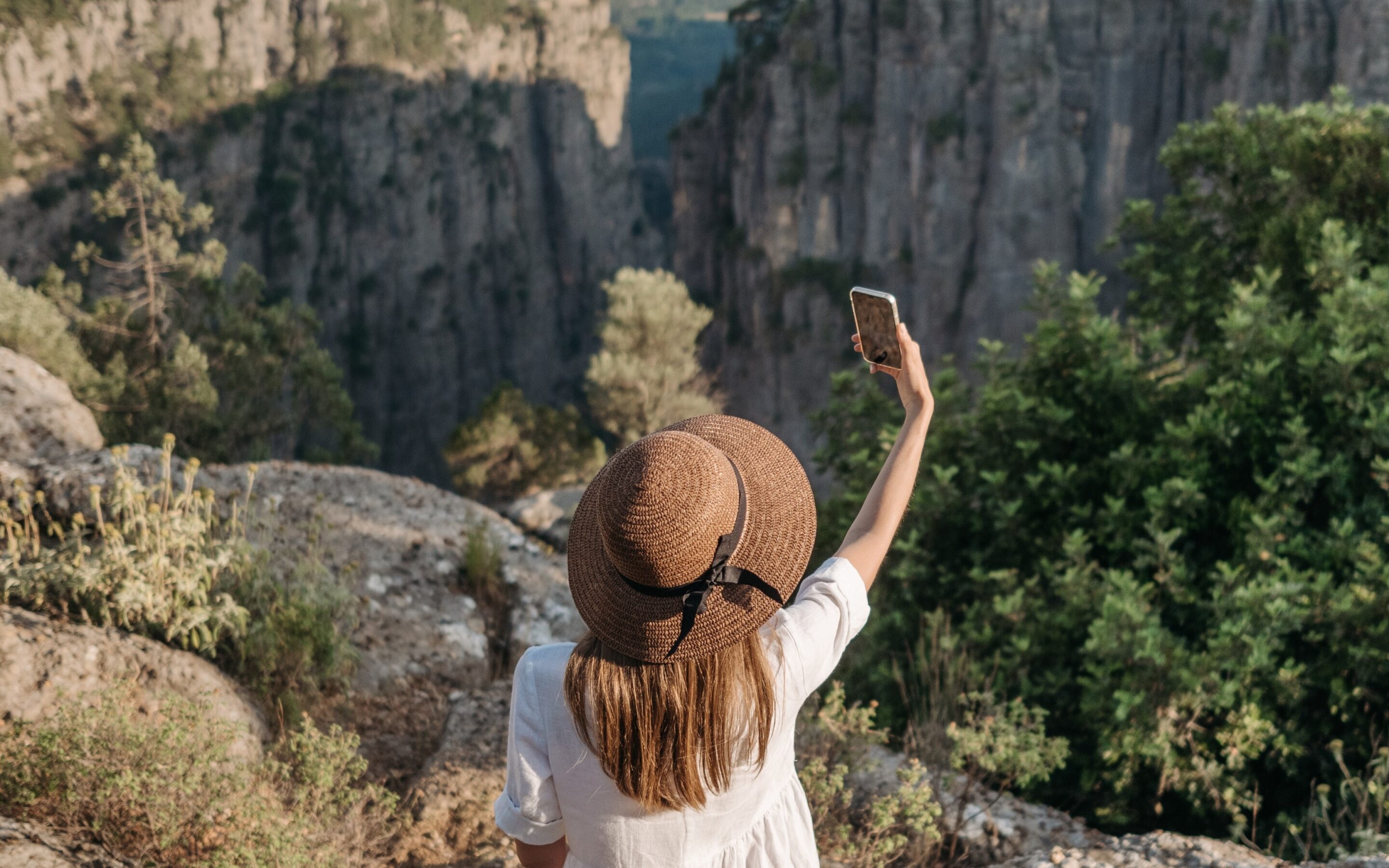 A woman standing in mountains and taking a selfie