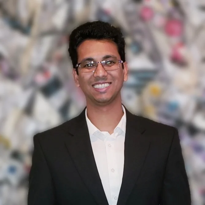 a man in a suit and glasses standing in front of a wall