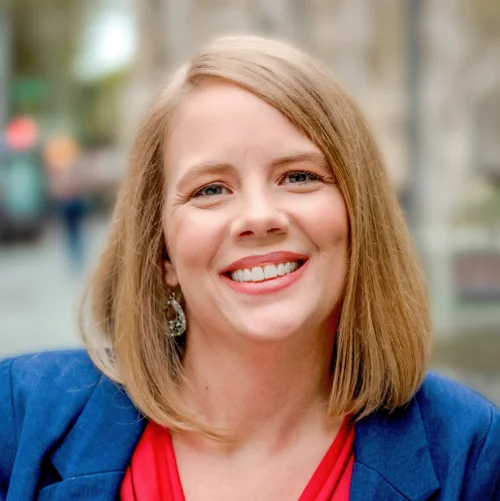 a woman in a blue jacket smiles at the camera